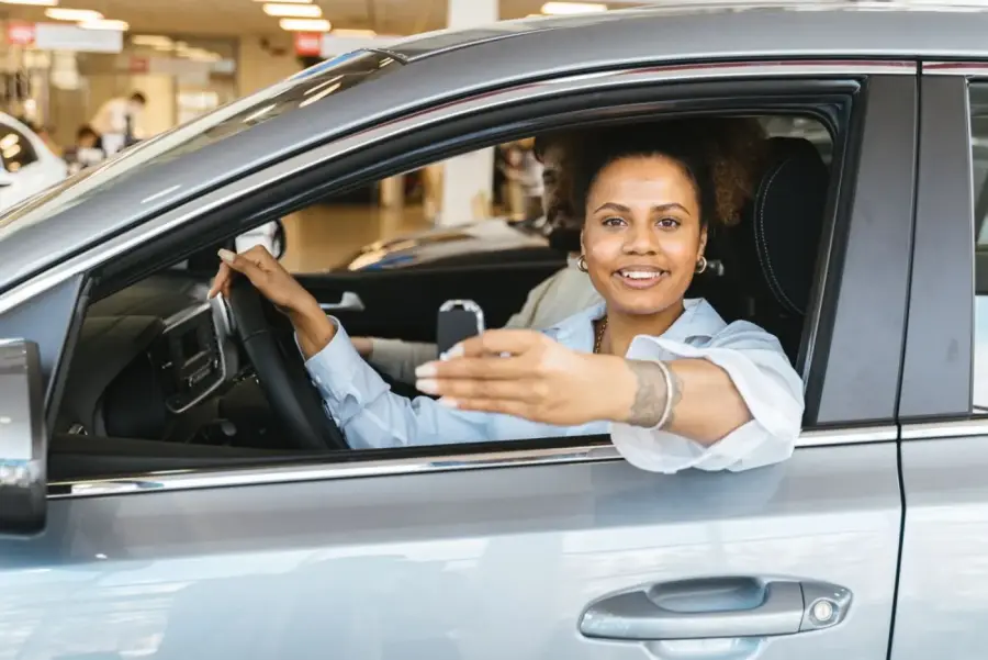 A customer smiling in the driver&rsquo;s seat holding her new car keys